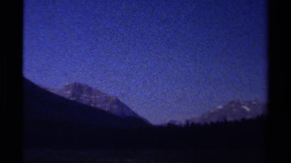Vintage 8mm mountain night view from British Columbia, with a dark ridge line and deep blue sky.