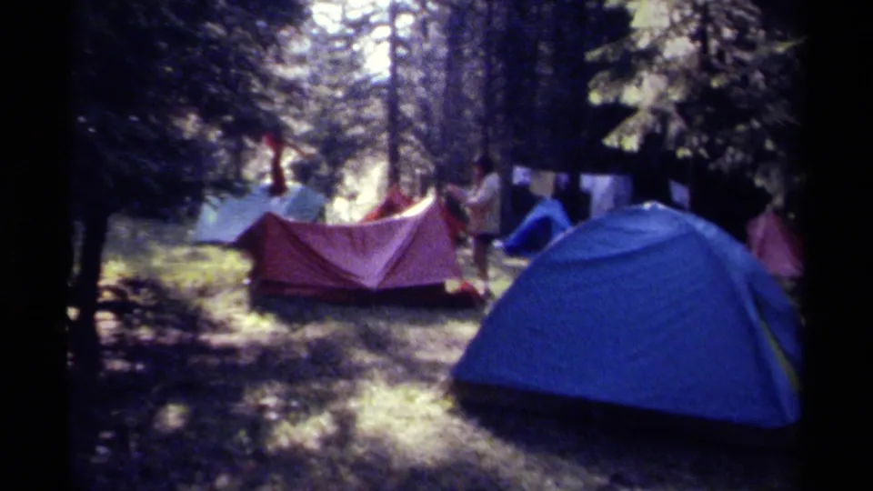 A shaded British Columbia campsite shows tents, campers, and hanging gear in soft 8mm home-movie footage from 1979.