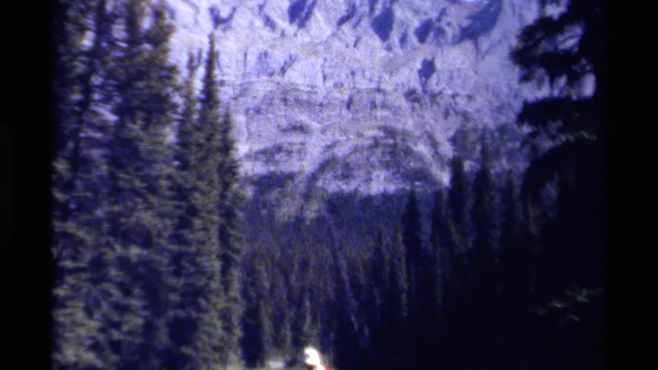 British Columbia mountain forest view on 8mm film, with a distant hiker partly visible near the lower edge.