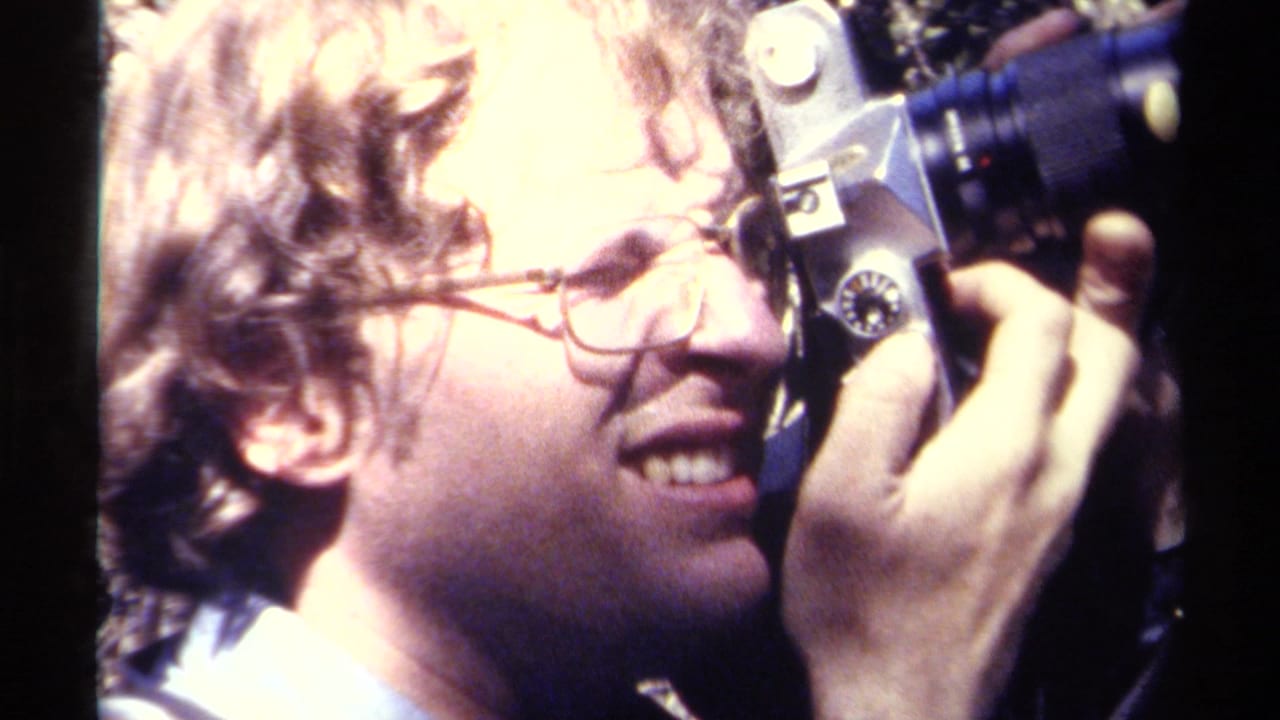 Young man with glasses films with a small movie camera in outdoor British Columbia home-movie footage from 1979.