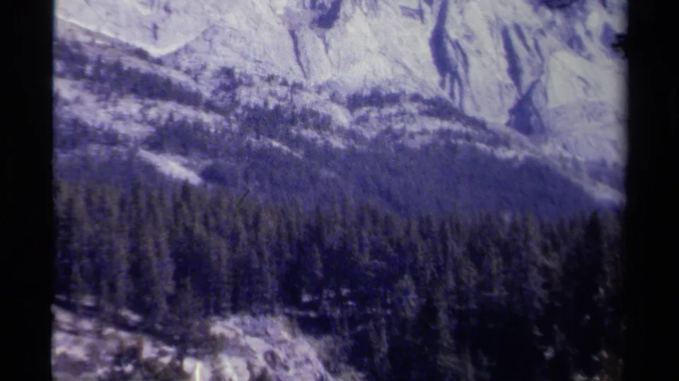 British Columbia mountain and evergreen forest view from a 1979 8mm home movie, with soft color and visible grain.