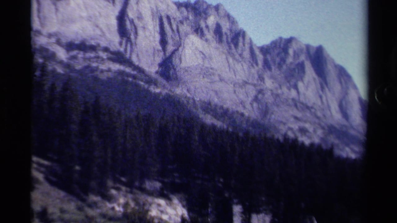 Rocky mountain ridge and dark forest slope with a narrow strip of sky.