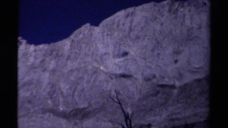 1979 British Columbia 8mm frame with a soft, close view of a pale rocky or snowy slope beneath a dark mountain shadow.