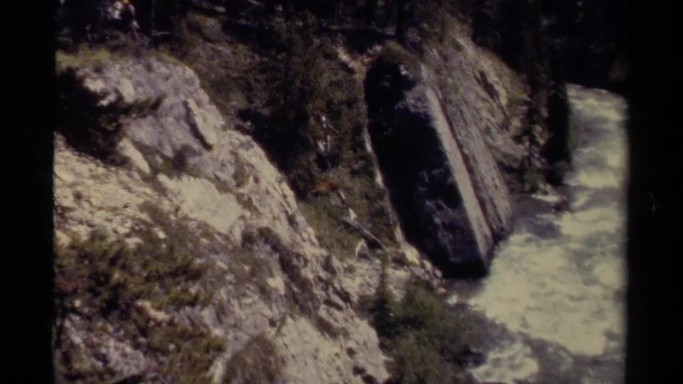 1979 8mm view of pale rapids moving through a rocky British Columbia canyon with steep banks.