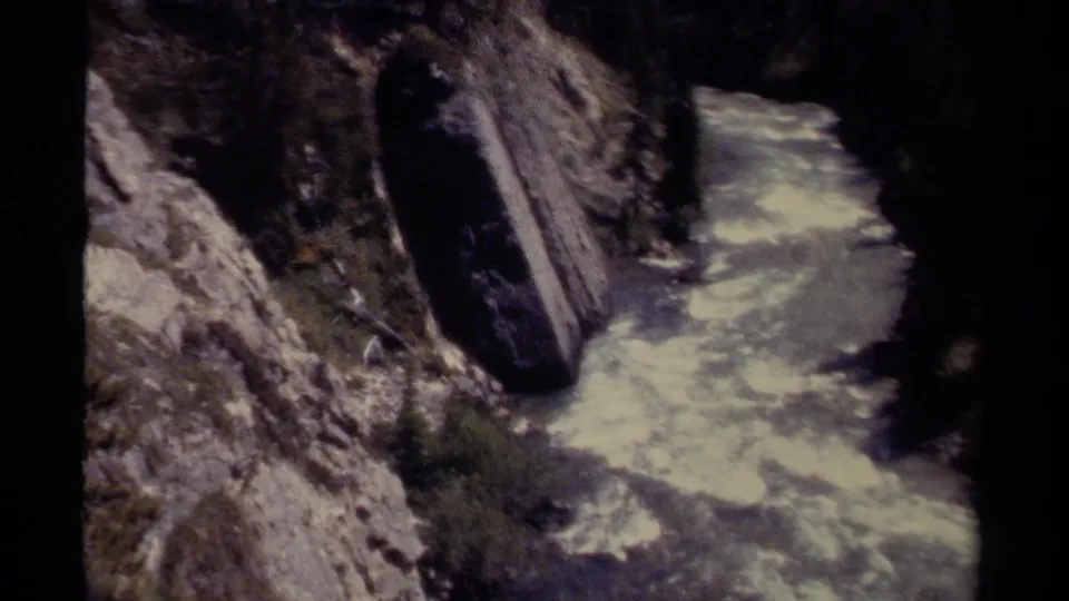British Columbia canyon rapids continue through steep rock walls in soft, grainy 8mm color.
