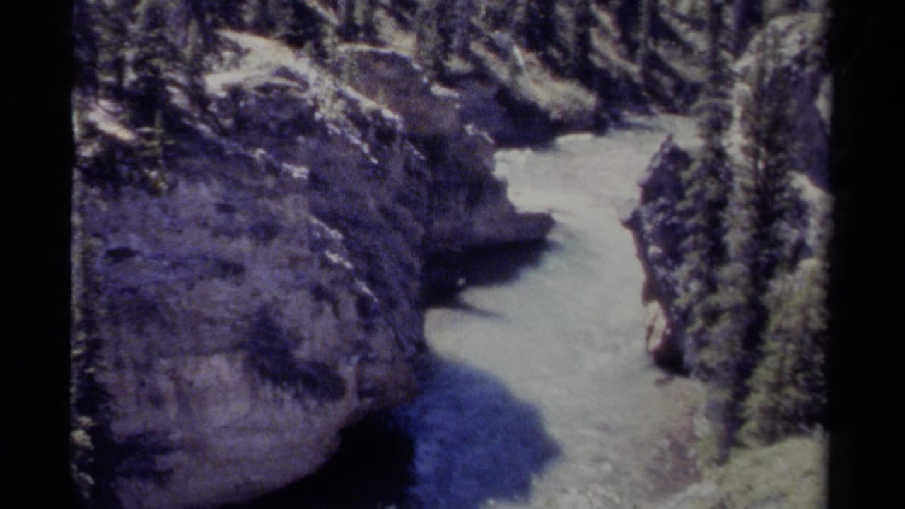 1979 8mm British Columbia home-movie frame showing a pale river moving through a narrow rocky canyon bordered by evergreen forest.
