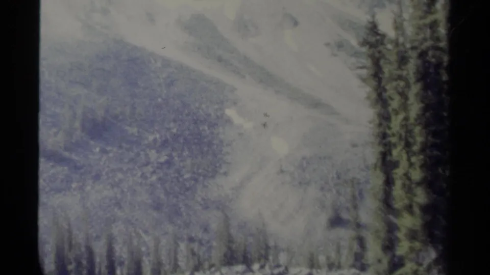 Faded 1979 8mm view of snow-dusted mountains and dark evergreens in British Columbia, Canada.