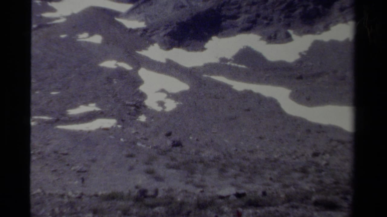 1979 8mm view of a British Columbia mountain slope with irregular snow patches, muted color, and visible film gate borders.