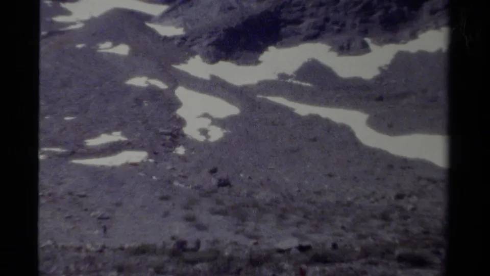 1979 8mm view of a British Columbia mountain slope with irregular snow patches, muted color, and visible film gate borders.