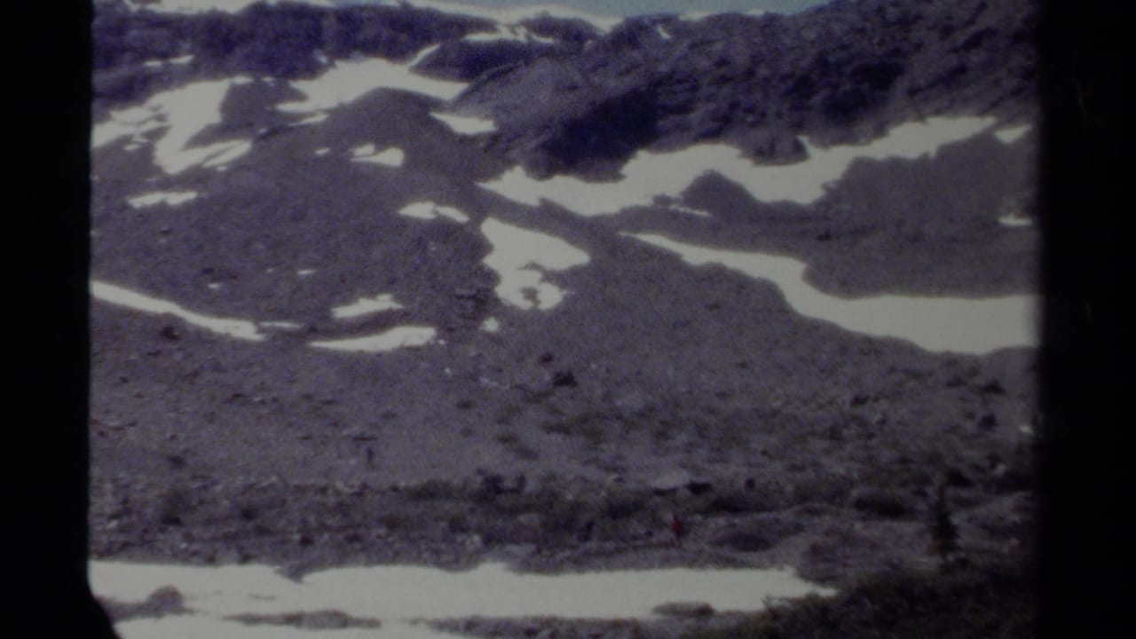 Distant rocky snowfield with a small red figure near the lower right area.
