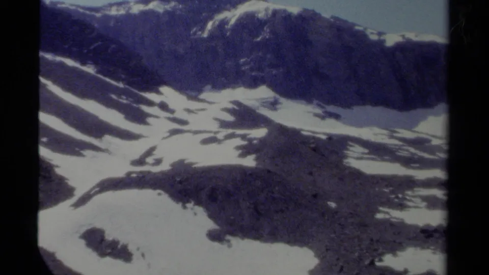 1979 British Columbia 8mm frame of a rugged mountain slope with scattered snowfields and soft analog color.