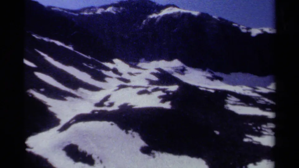 1979 British Columbia 8mm frame with high-contrast snowfields, dark ridges, and visible analog grain near the end of the pan.