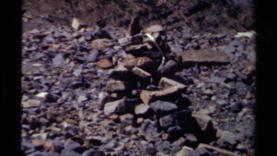 1979 British Columbia frame showing the cairn largest in view, set on gravel with patchy snow and dark mountain rock behind.
