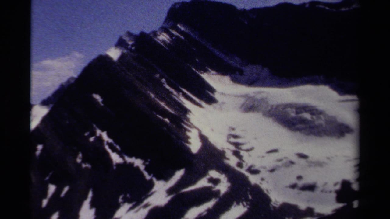 Snow-streaked dark mountain slope beneath a blue sky.