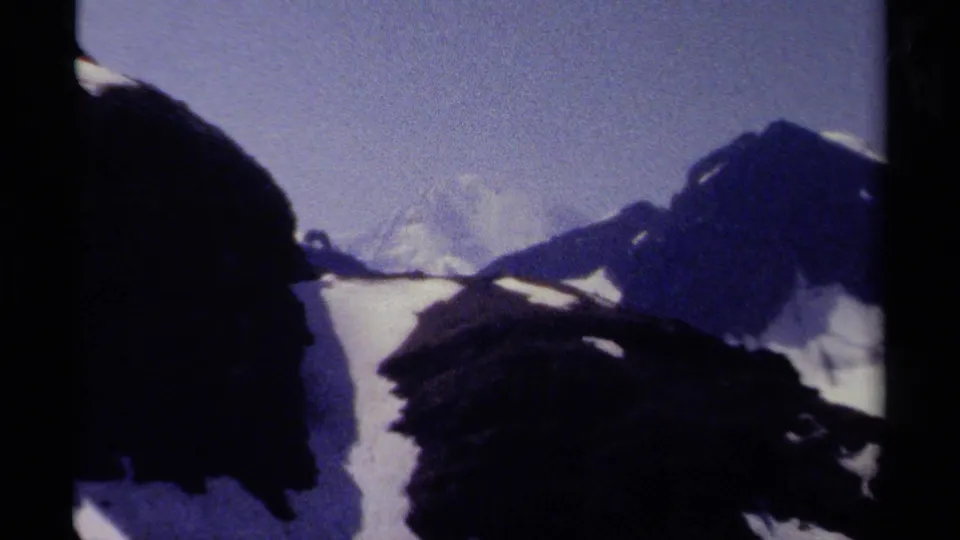 British Columbia 8mm mountain view with a pale snowfield, distant peak, and dark ridges in soft blue-purple color.