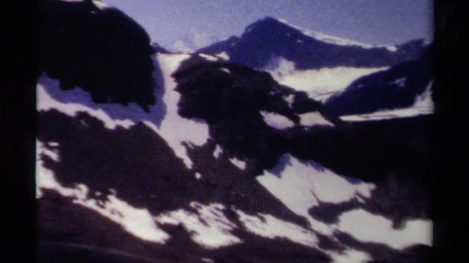 1979 8mm home-movie view of a snowy mountain basin in British Columbia, framed by dark ridges and distant peaks.