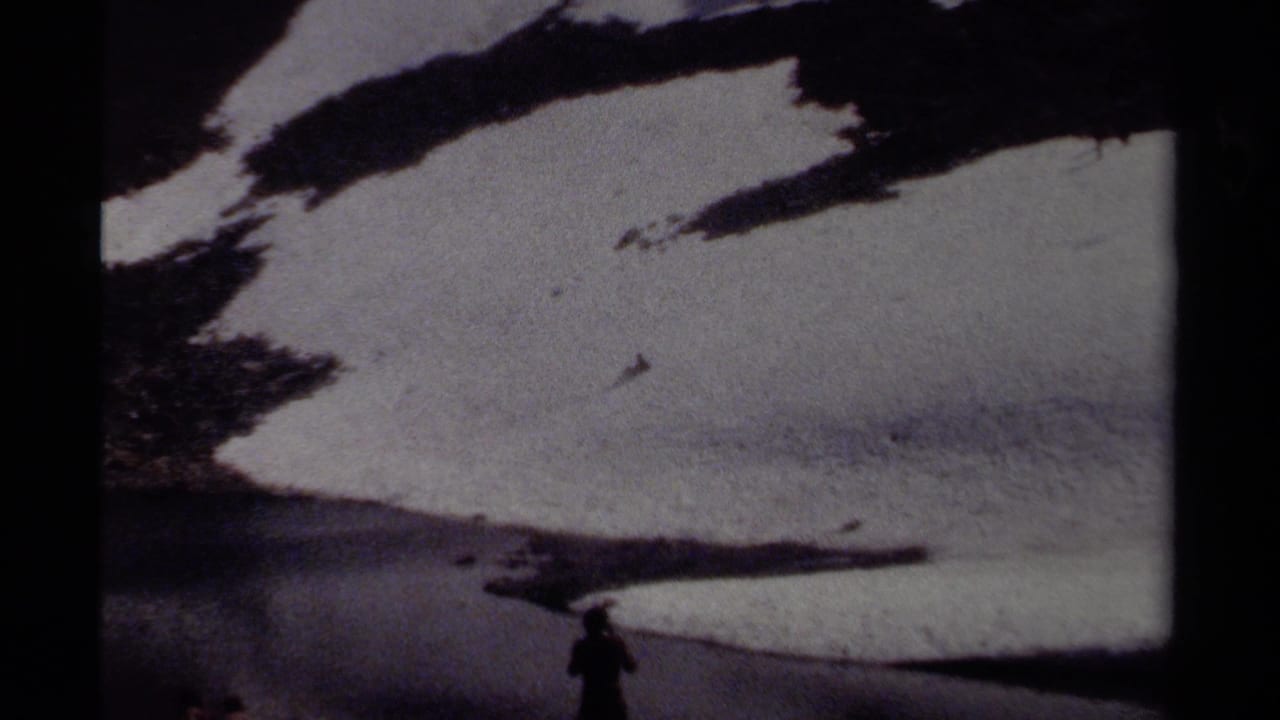 A silhouetted person stands near snow, rock, and meltwater in a British Columbia alpine landscape from 1979 8mm footage.
