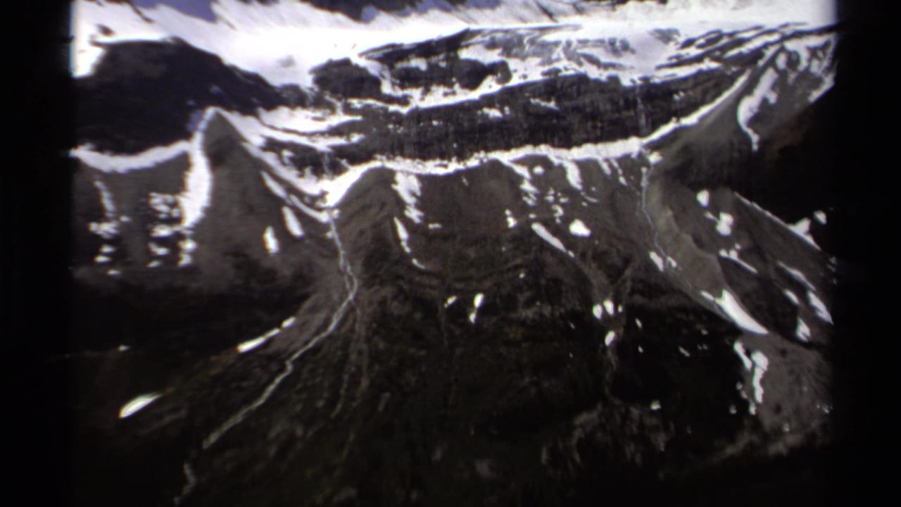 Snow-dusted mountain slopes and dark alpine terrain seen from above.