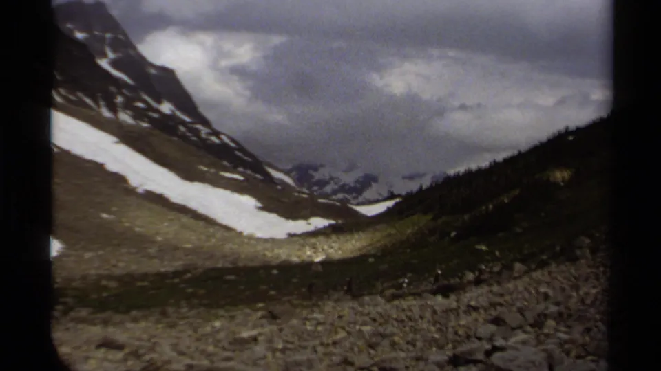 British Columbia alpine landscape on 8mm film, showing snow bands, dark ridges and an overcast sky.