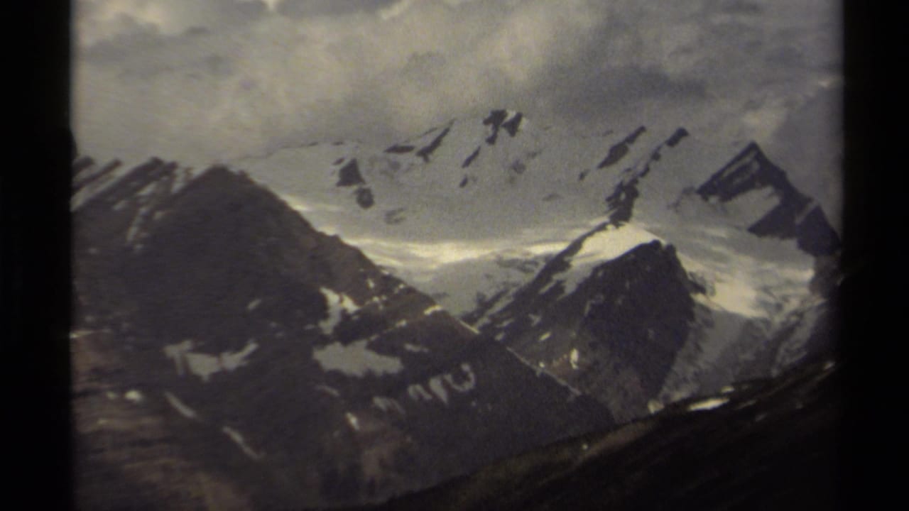 Snow-covered British Columbia mountain range on 8mm film, with dark slopes in the foreground and cloud cover above the peaks.