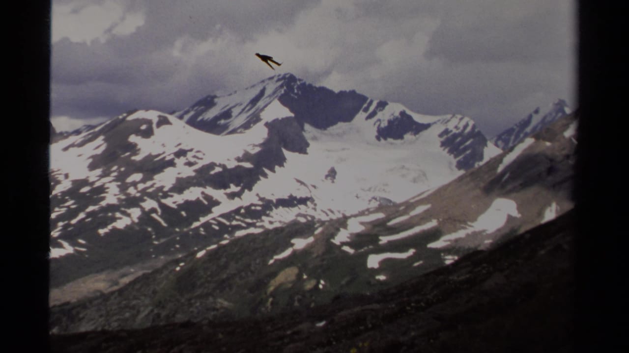 1979 8mm home-movie view of snow-streaked mountains in British Columbia beneath a cloudy sky, with dark frame edges visible.
