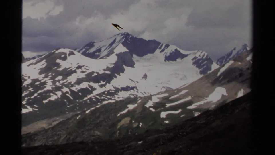 1979 8mm home-movie view of snow-streaked mountains in British Columbia beneath a cloudy sky, with dark frame edges visible.