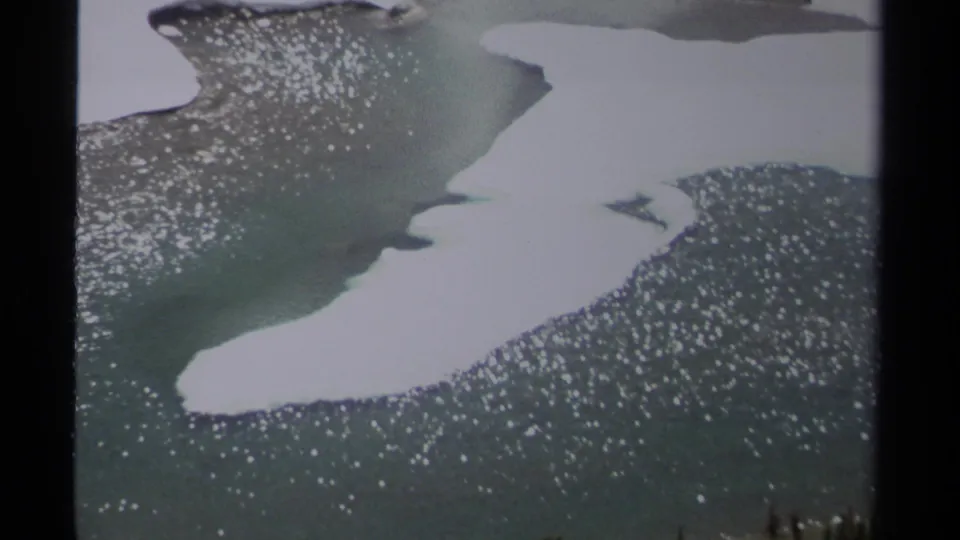 8mm British Columbia snowmelt detail with a white snow patch, turquoise water, dark rock, and bright reflected highlights.