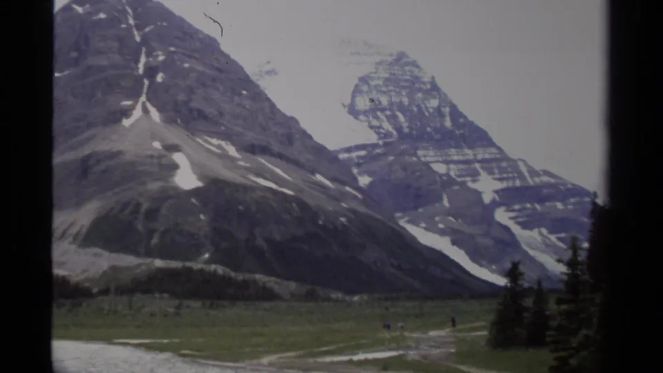 A visitor-shot mountain view in British Columbia shows meadow foreground and tiny distant people.