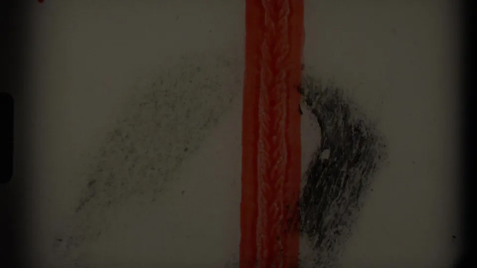 End-frame or film-leader-like view with a vertical red strip, scratches, and darkened exposure.