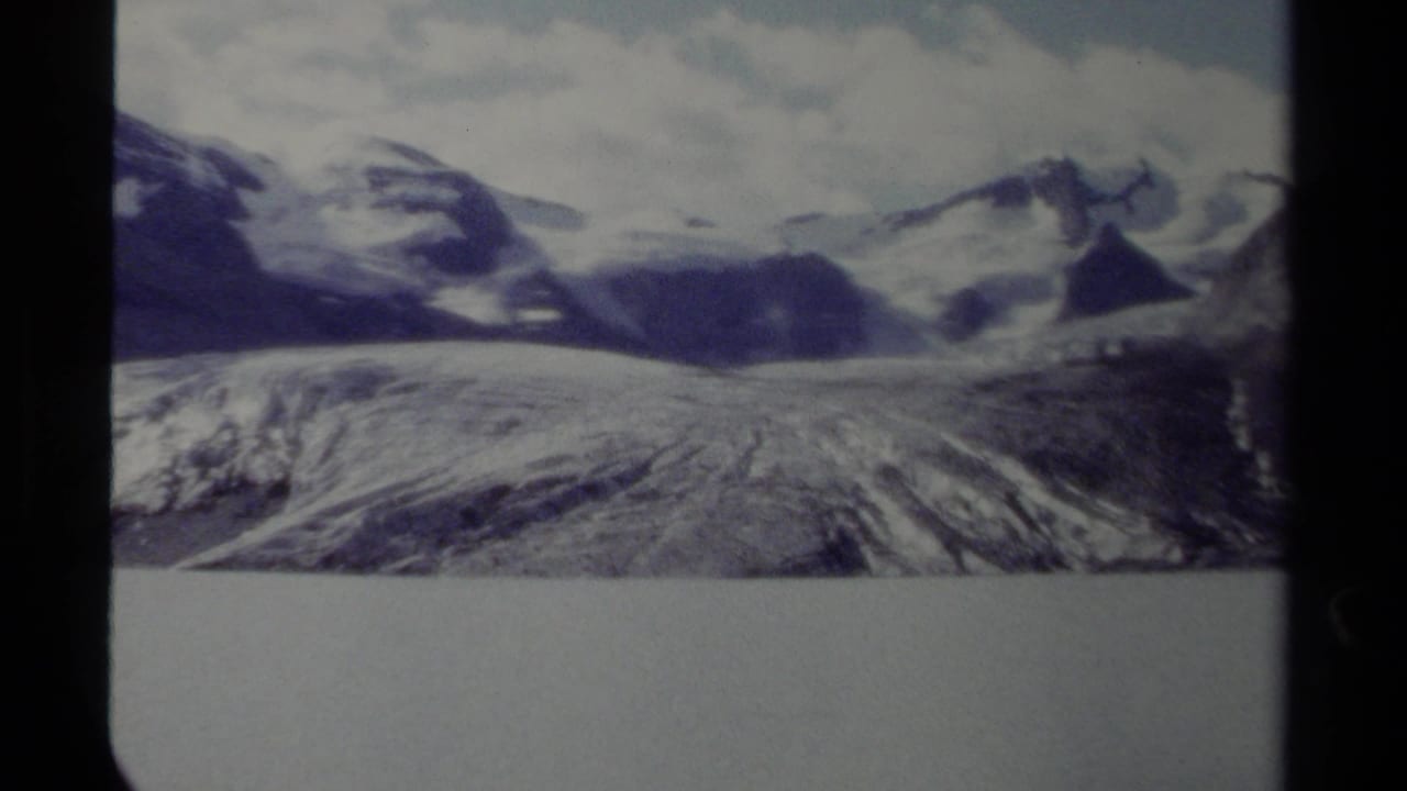 Wide glacier and snow-covered peaks framed by vertical film gate edges.