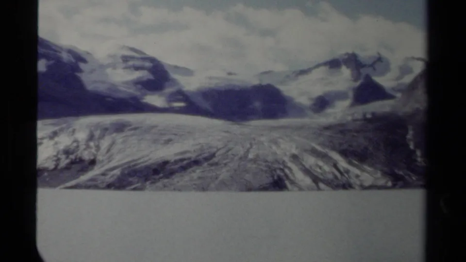 British Columbia mountain and glacier view on 8mm film, with cloudy sky and visible frame borders.
