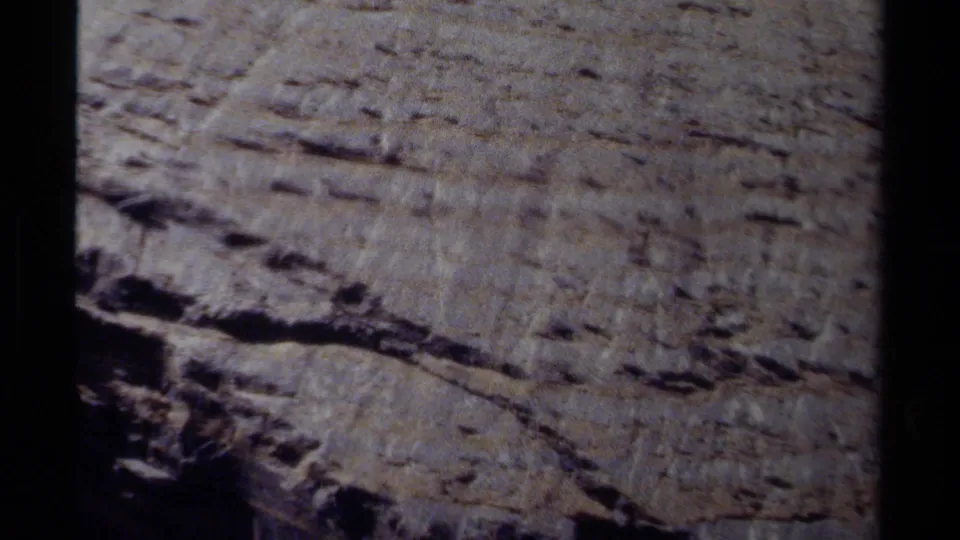 Close-up 8mm view of a layered rock face in British Columbia, showing cracks and striated surface patterns.