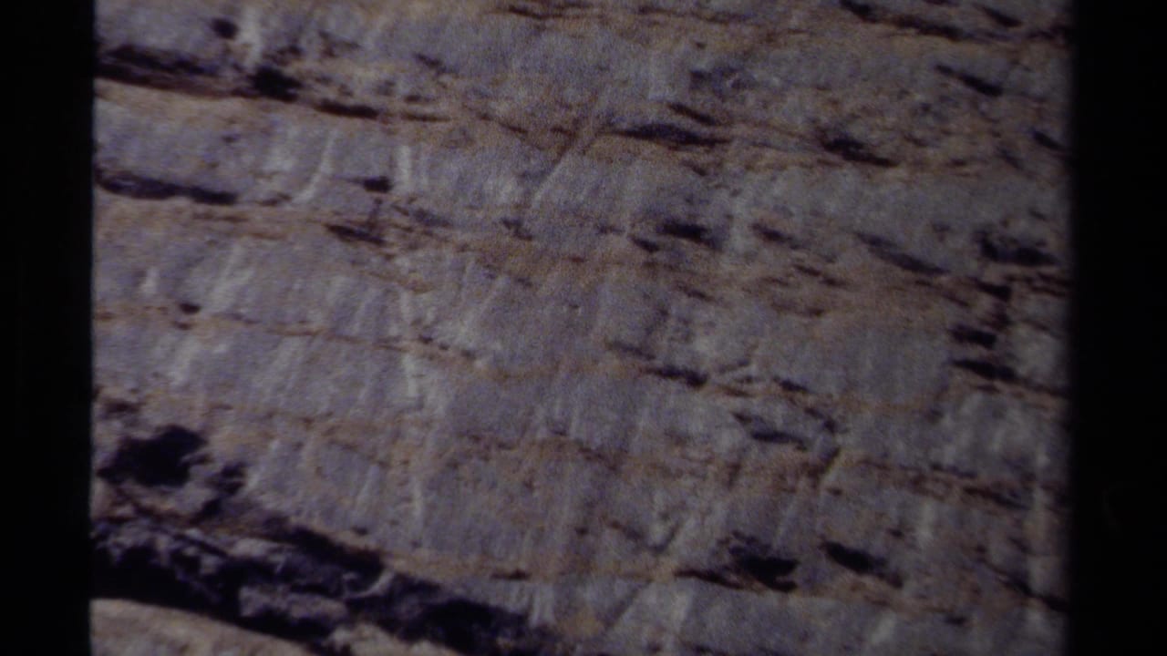 Sheer rock face with horizontal ledges and deep shadows.