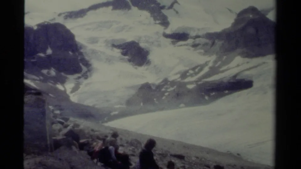 1979 British Columbia home-movie view of hikers at the base of a broad snow-covered alpine landscape.