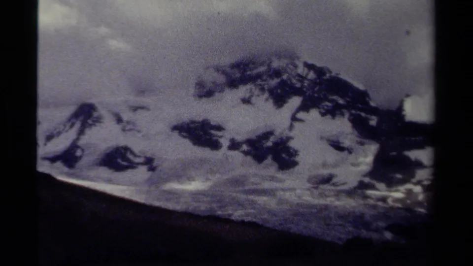 1979 home-movie frame of a snow-covered mountain slope in British Columbia, softened by grain, exposure variation, and gate edges.