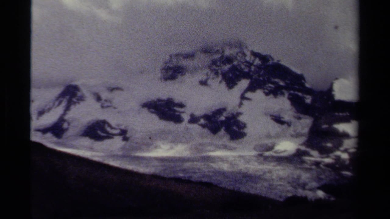 1979 8mm view of a snow-covered mountain ridge in British Columbia, with dark slopes and cloudy sky.