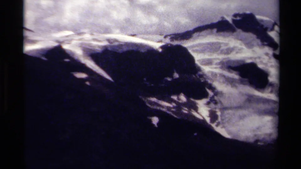 Late-1970s 8mm mountain view in British Columbia, with snowy ridges, exposed rock, and cloudy sky.