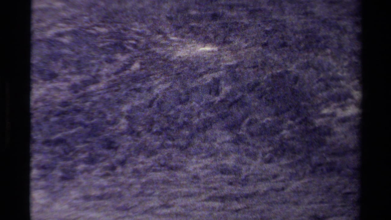 Dark rocky mountain surface with rough texture and pale streaks.