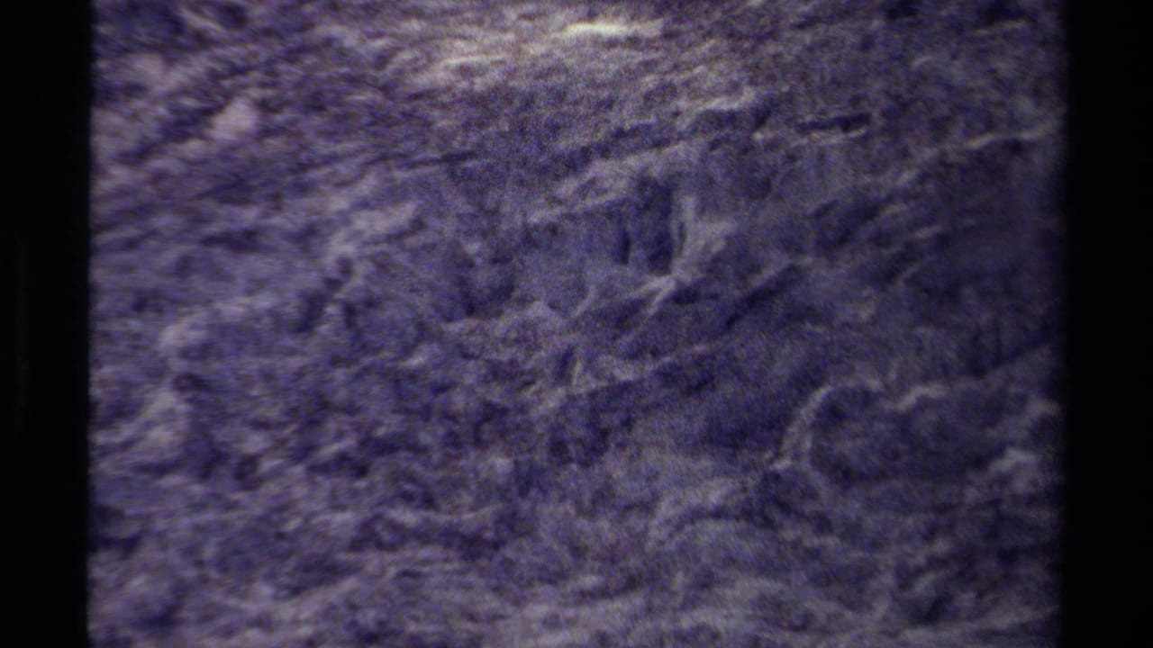Textured mountain rock face with crevices and pale marks.