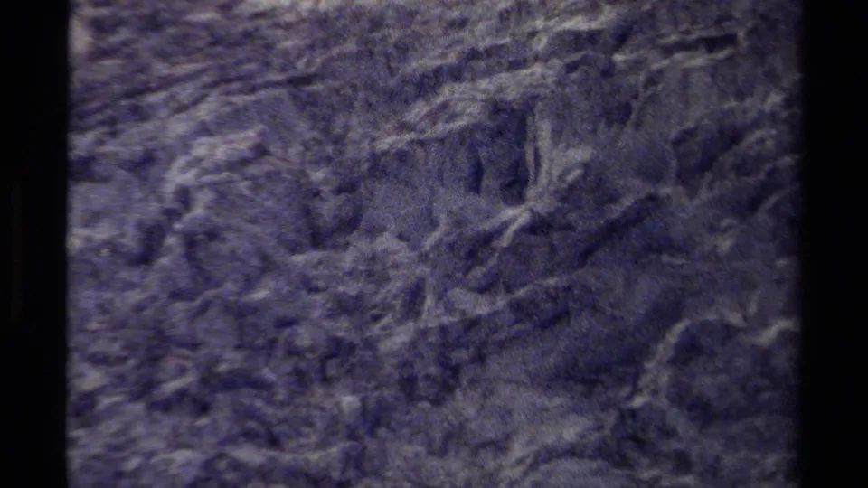 1979 British Columbia 8mm frame showing dark layered rock, visible cracks, rough stone surfaces, and heavy home-movie grain.
