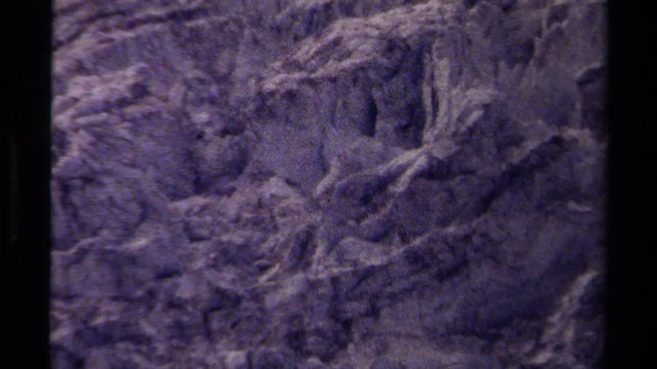 1979 British Columbia 8mm frame showing a rugged rock face with soft focus, heavy grain, and a cool color cast.