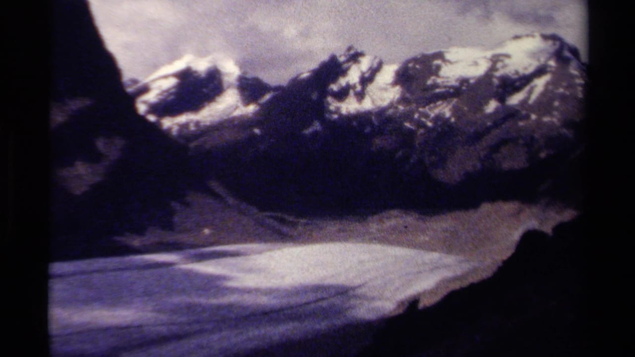 Snow-capped mountain ridge above a pale valley or snowfield.