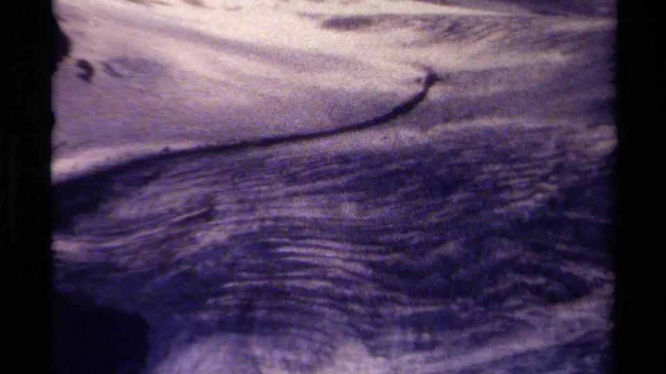 1979 British Columbia home-movie still showing textured ripples over a rocky streambed, softened by grain and color fading.