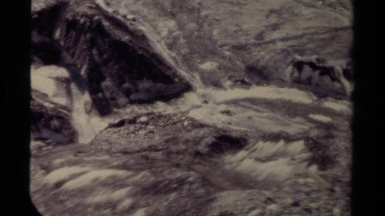 1979 British Columbia 8mm frame showing turbulent water moving around jagged rocks in a mountain stream.