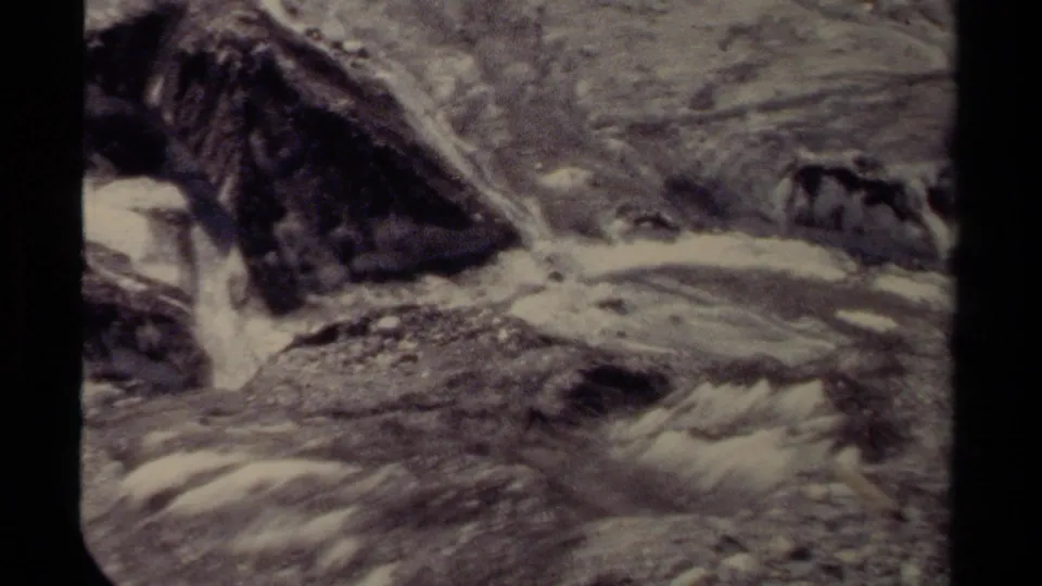 1979 British Columbia 8mm frame showing turbulent water moving around jagged rocks in a mountain stream.