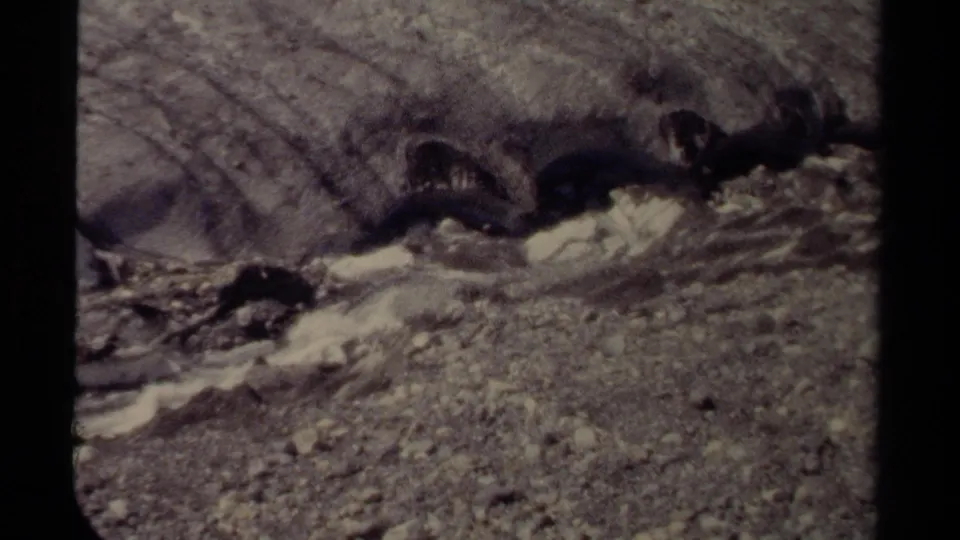 1979 British Columbia home-movie frame of whitewater moving through a rocky creek with rough gravel banks.