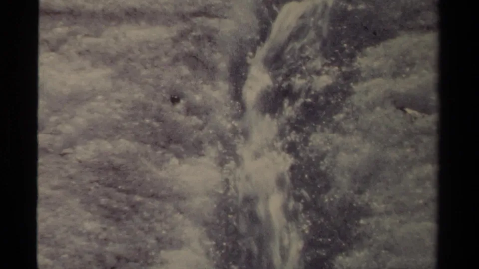 1979 British Columbia 8mm frame with water flowing down a cut in the ice over rough frozen ground.
