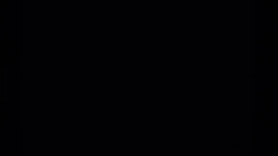 Underexposed 8mm transition frame with a sliver of rocky terrain visible at the left edge.