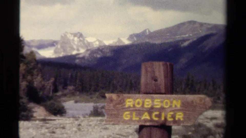 Wooden Robson Glacier sign stands before forest, mountains, and snow-capped peaks in British Columbia, 1979.