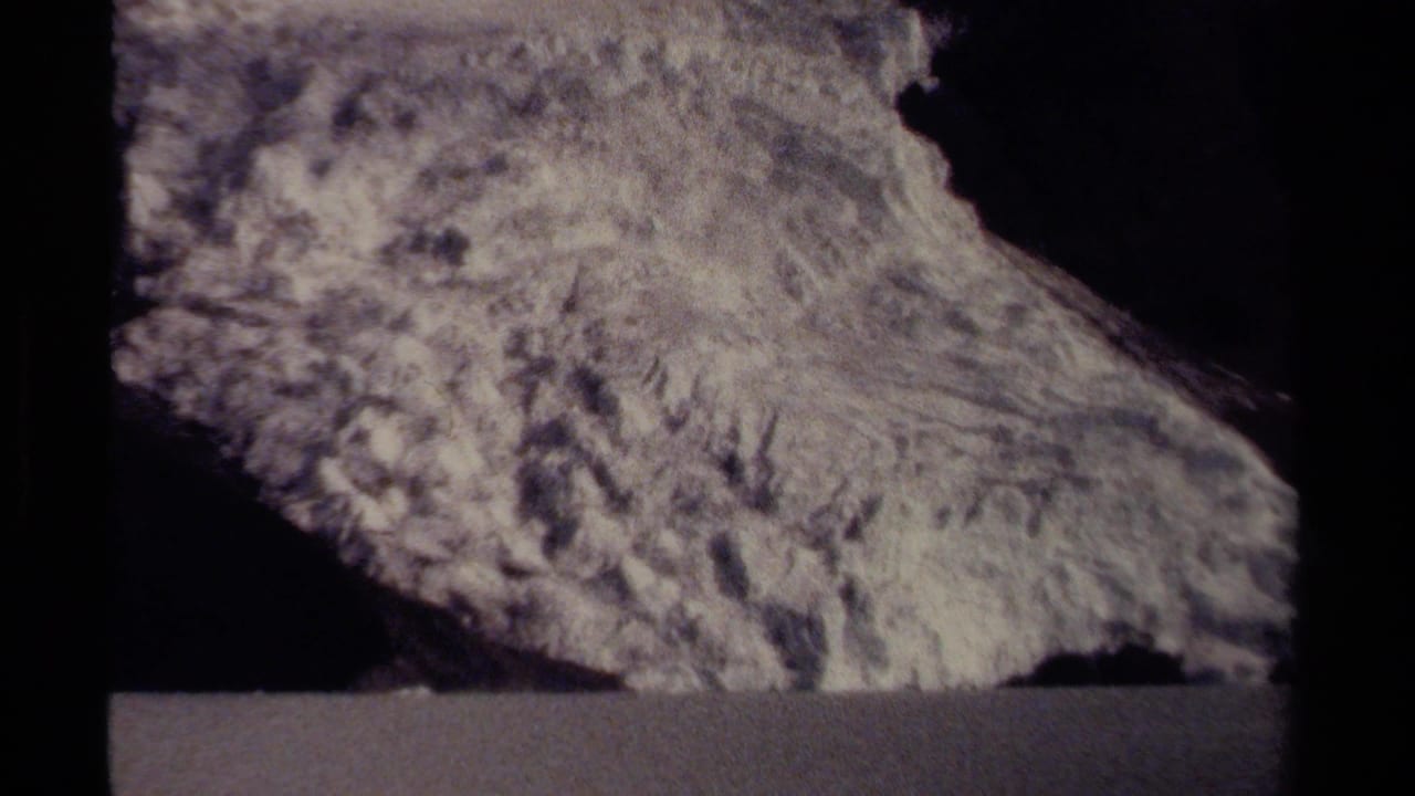 Large textured rock formation above a dark horizontal roadside-like foreground band.